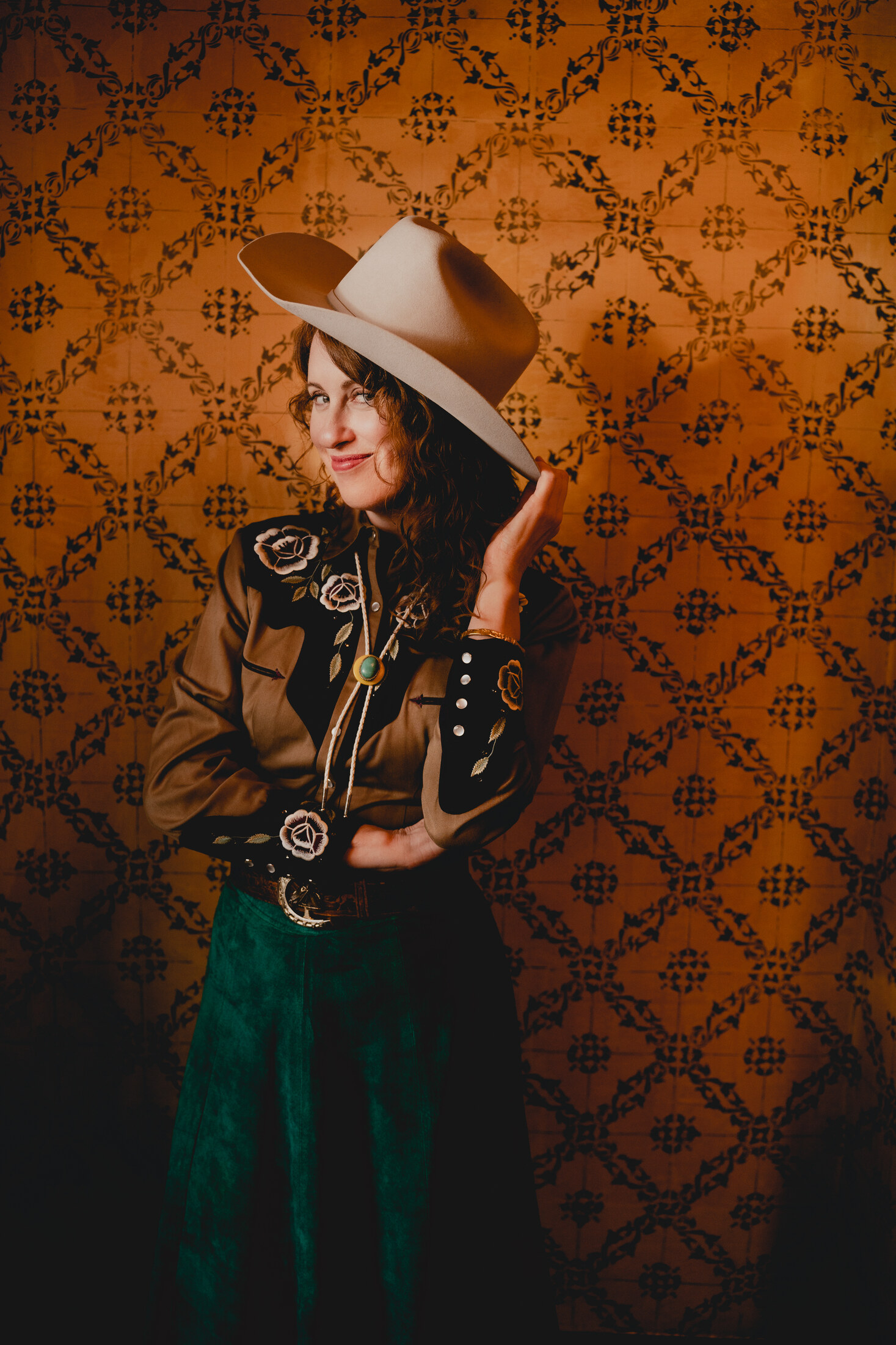 Adele in western wear against patterned wallpaper