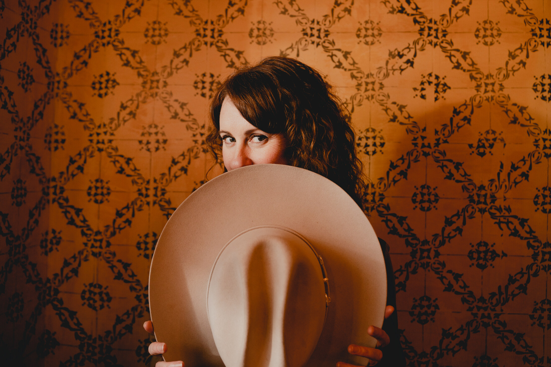 Adele peering over a cowboy hat