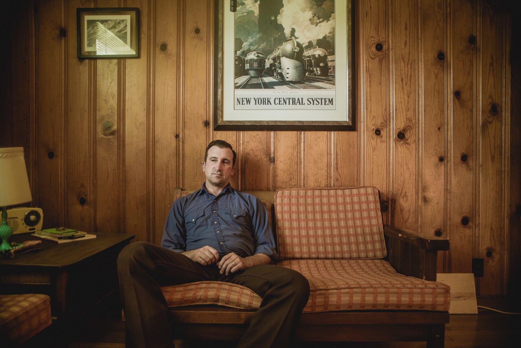 Matt Campbell seated at home beneath a vintage railway print