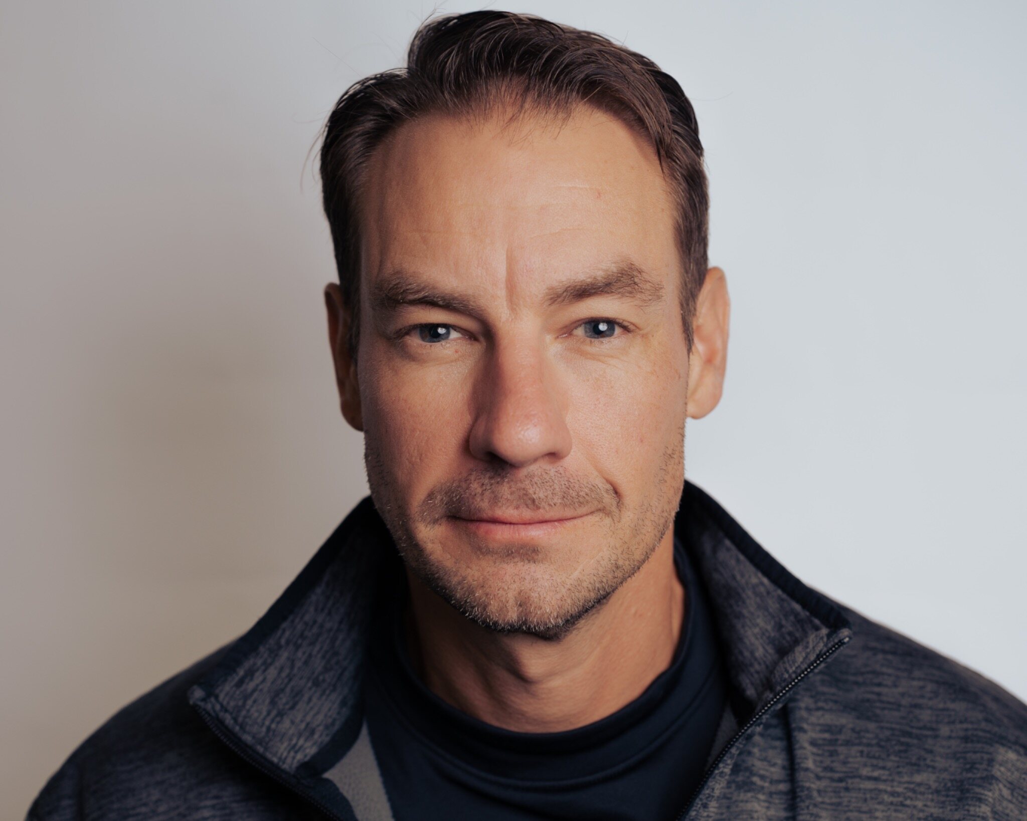 Man in a dark quarter-zip against a gray studio background